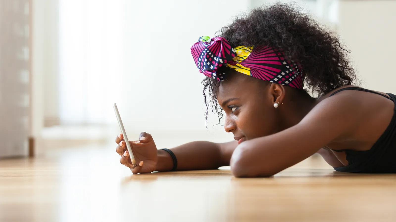 A young woman looking at her phone, used to represent the experience of an adult with ADHD knowing what they want to do, recognising it matters, and still being unable to begin.