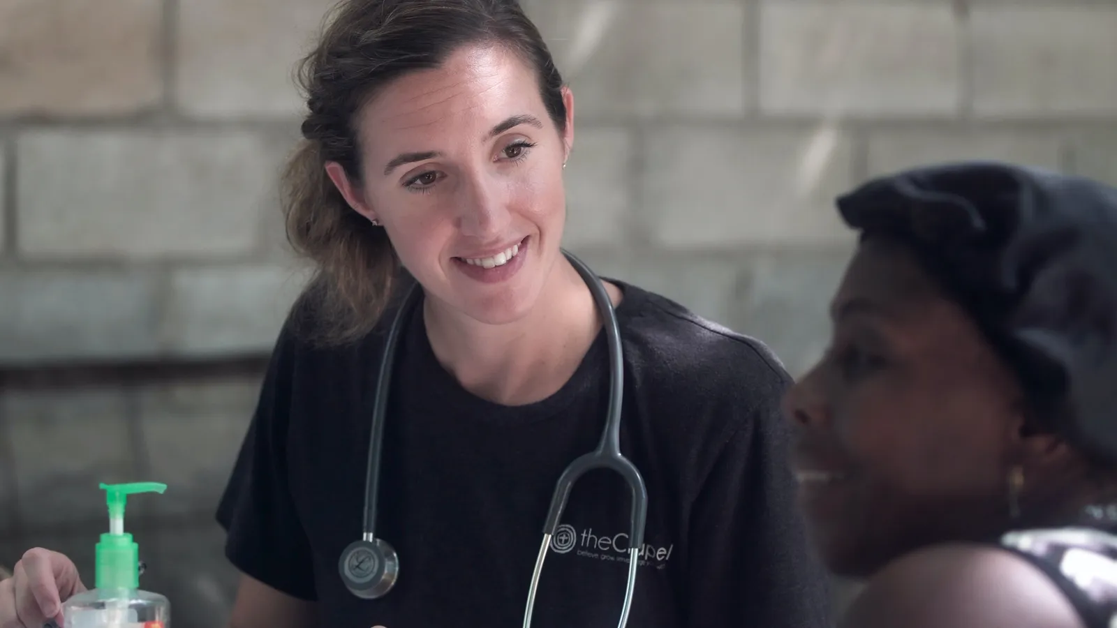 A smiling doctor with a stethoscope talking with a patient.