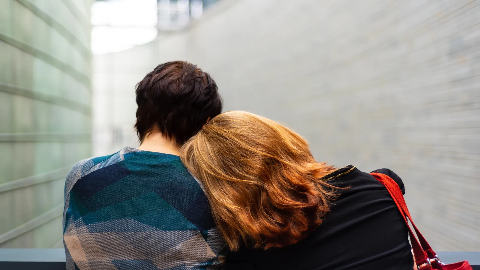 A person rests their head on another person's shoulder. The image is used to represent how human regulation often happens through proximity and physical co-presence with another person, not through individual effort alone.